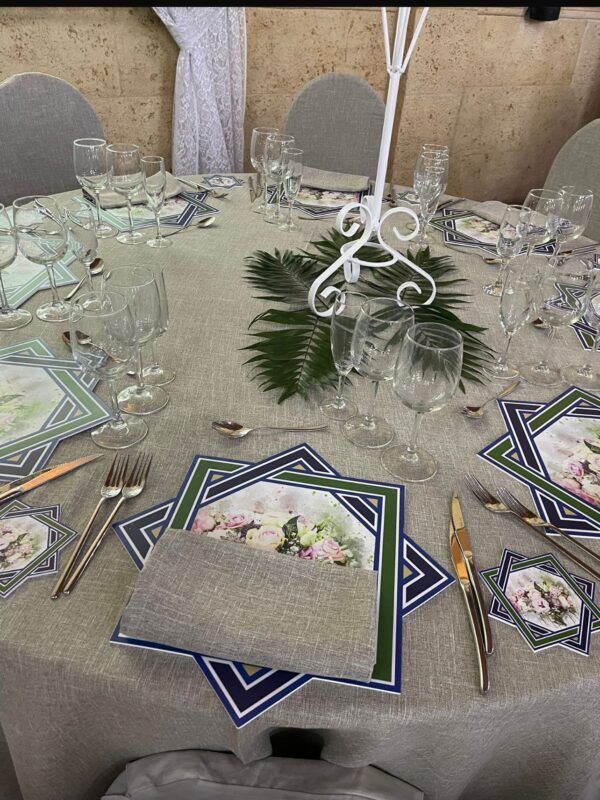 Mesa elegante decorada con mantel gris, servilletas a juego y platos decorativos con diseño floral y geométrico