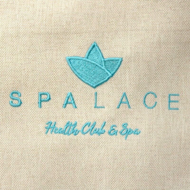 Logotipo bordado de SPALACE en hilo azul con hoja decorativa y texto wellness