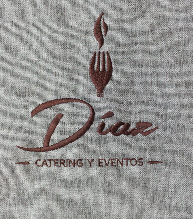 Logotipo bordado de Díaz Catering y Eventos con tenedor y llama sobre fondo textil