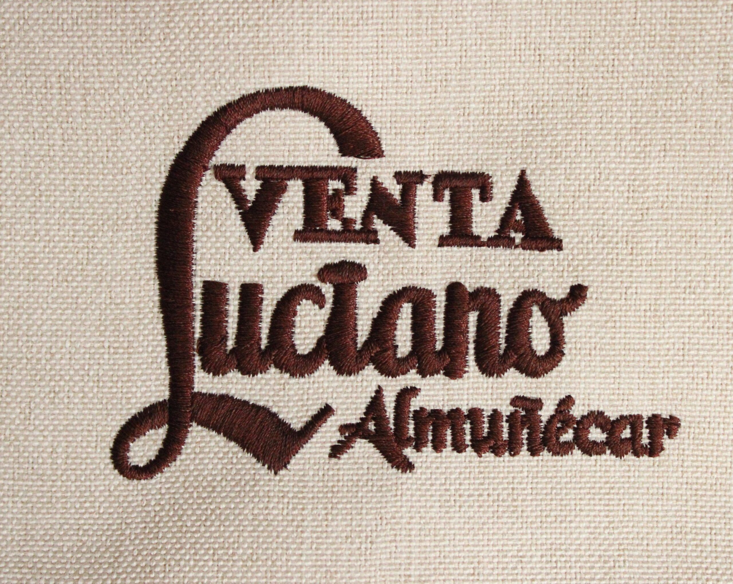 Logotipo bordado de Venta Luciano Almuñécar en hilo marrón sobre fondo beige